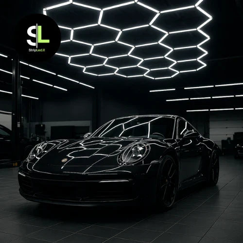 Auto sportiva nera parcheggiata in un'officina moderna con illuminazione LED esagonale sul soffitto e logo StripLed.it