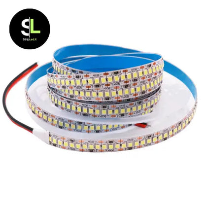 Dettaglio ravvicinato di una striscia LED con chip SMD e retro adesivo blu su fondo bianco con logo StripLed.it