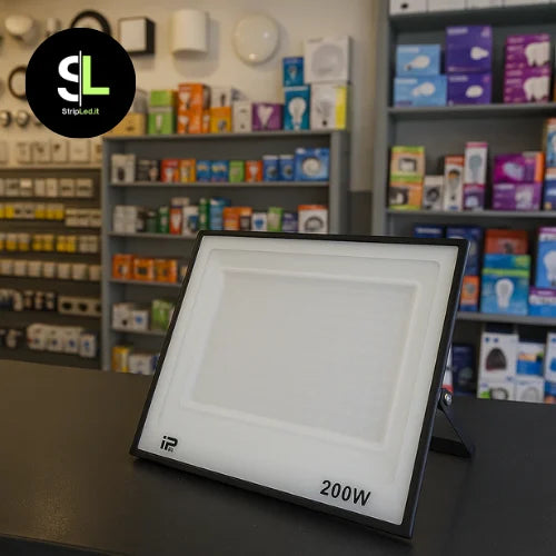 Faro LED 200W esposto su bancone di negozio con scaffali di prodotti elettrici sullo sfondo e logo  StripLed.it”