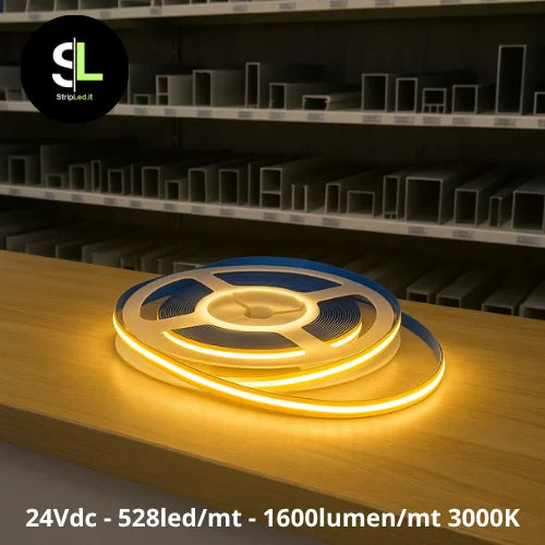 Striscia LED COB 24V bianco caldo 3000K accesa su banco da lavoro e logo StripLed.it