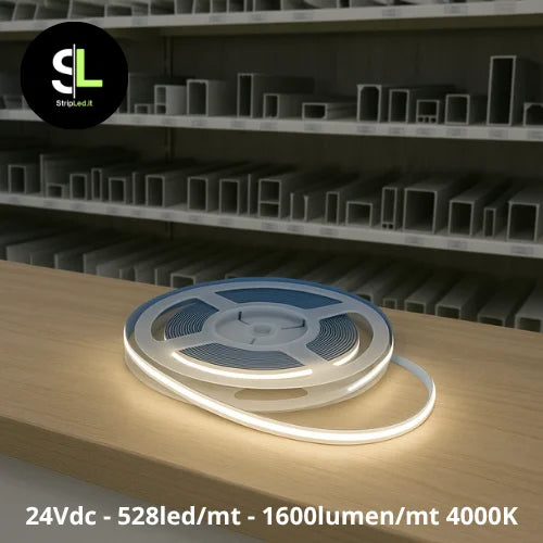 Striscia LED COB 24V bianco naturale 4000K accesa su banco di magazzino con scaffali e logo StripLed.it”